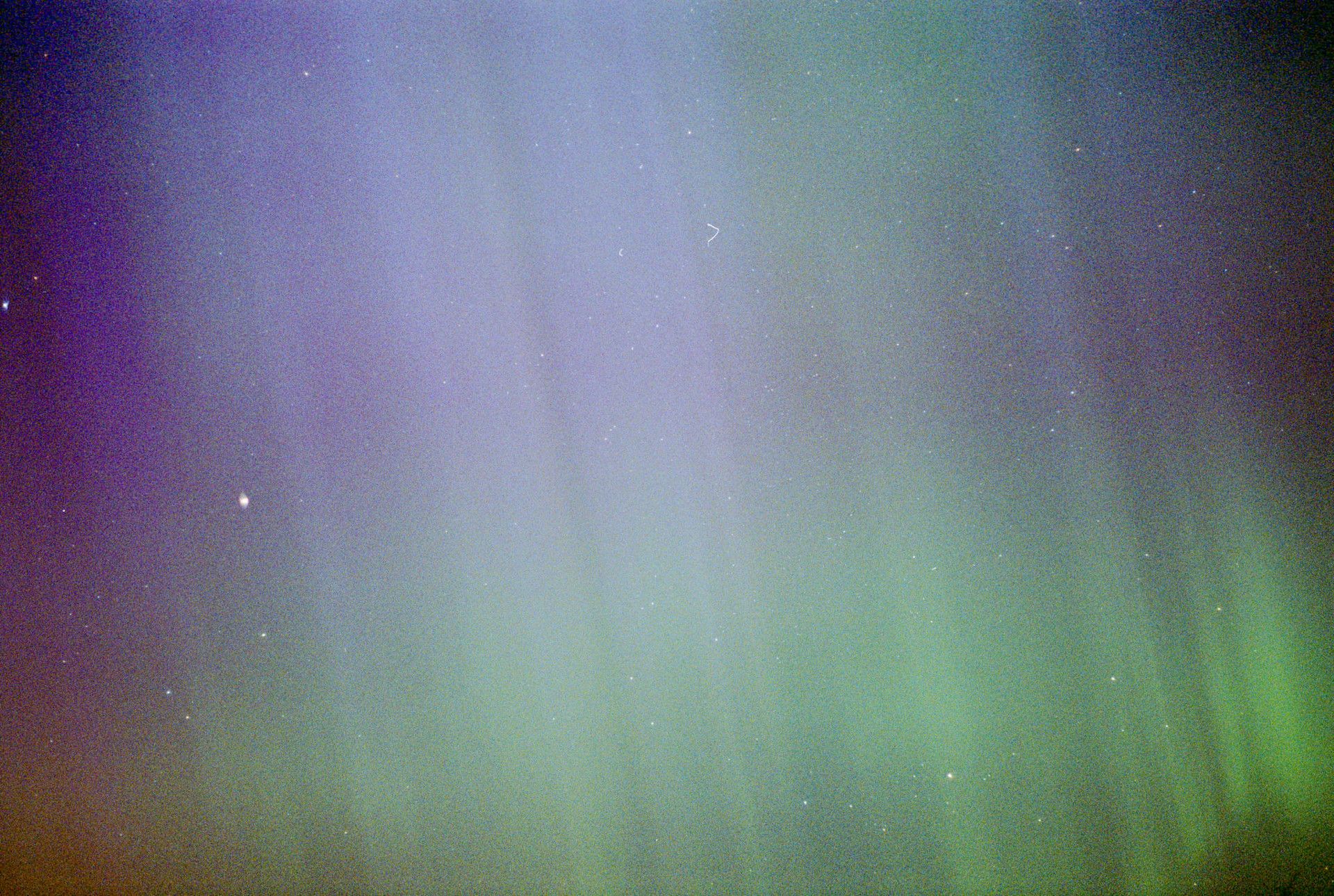 A colorful photograph of the aurora borealis. The sky is a deep blue with streaks of all different colors visible.