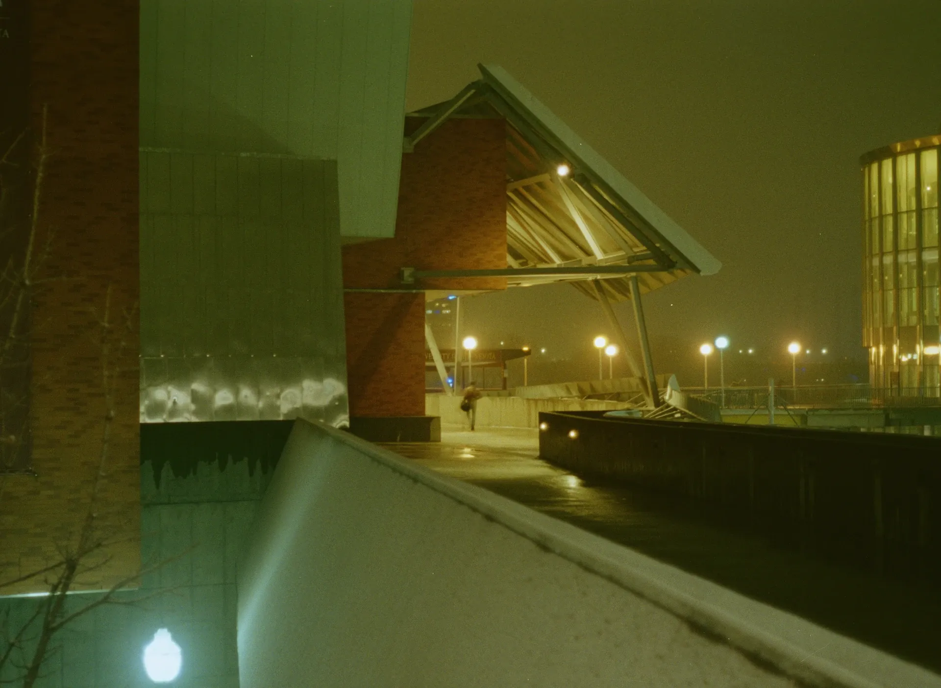 A landscape photo of a college campus on a snowy day with a single pedestrian in the center of the frame.