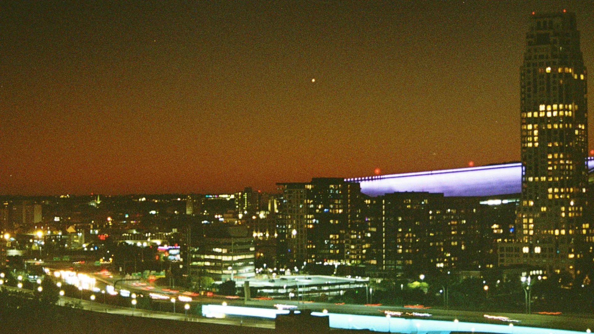 A grainy landscape photo overlooking Minneapolis's skyline and I-35W at night.